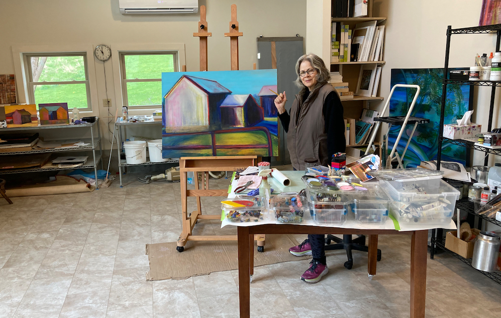 Dona Mara Friedman in her new studio. She is standing in front of a table of oil sticks and encaustic paints. 